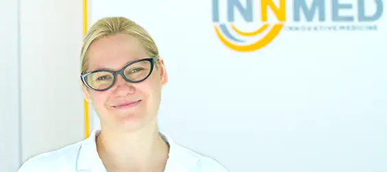 Vaistų konsultantės portretas, vaistininkė su akiniais, šypsosi, sveikatos ir vaistų tema.